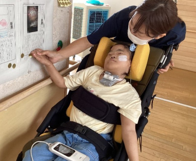 廊下に掲示された新聞に、いいねシールを貼っている場面