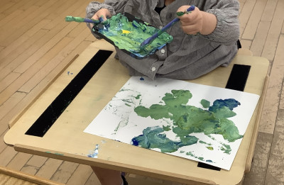 パレットに絵の具をのせて筆で絵具を混ぜながら画用紙に色付けしています