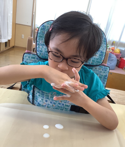 泡絵の具を両手で混ぜ合わせて楽しんでいます。