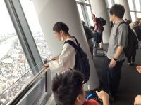 展望台から生徒が外を眺めている。窓の外に川が見える。