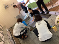 ４名の保護者が協力して浴室を清掃している様子。