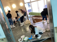 複数名の保護者が協力して浴室を清掃している様子。