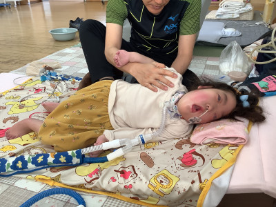 横向きに寝て教師が背中に手を当てたことを感じて力を入れたりぬいたりしています。