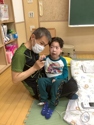 教師の膝の上に座って右手を上げたり下げたりする学習をしています