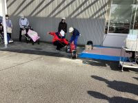 一人の職員が発電機のひもをひっぱり、もう一人が発電機をおさえている