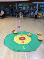 １人の男の子が木の棒を使用してカーリングストーンをおしている。周りでは他の参加者が見守っている。