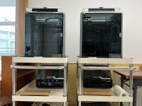 教室内に設置された2台の3DプリンターCreality K1 MAX。どちらも金属製のワゴンの上に置かれ、プリンター下段にはカラーシステムが置かれている。