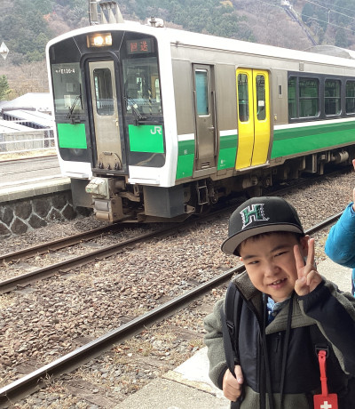 ホームで電車を待つ間に停まっていた電車をバックに記念写真を撮っています