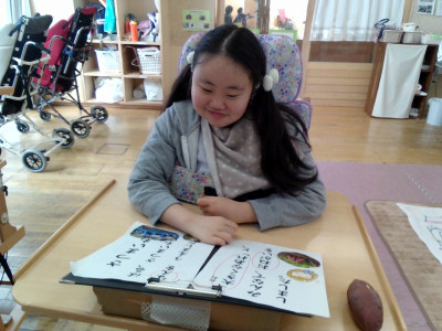 女子児童がプリントに貼った写真を笑顔で見ています