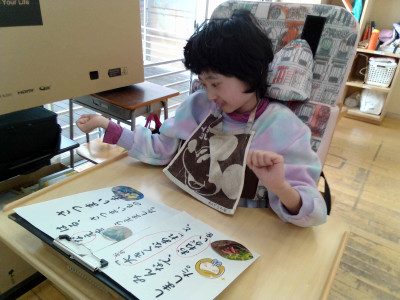 女子児童がプリントに貼った写真を笑顔で見ています